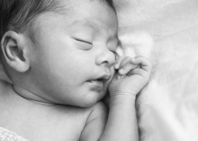 A newborn cradled in a parent's hands
